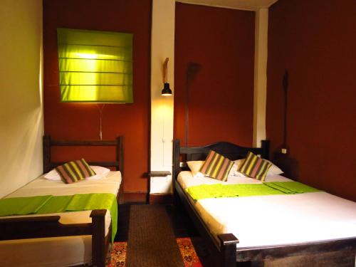 two beds in a room with red walls at Hostel La Casona Don Juan in San Gil