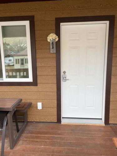 a white door on the side of a house with a bench at ParkWay Yellowstone Guest House Room #1 in Gardiner