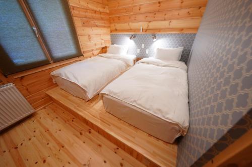 two beds in a room with wooden floors and windows at Forrest Kitakaruizawa in Tsumagoi