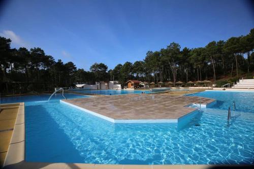 a large swimming pool with blue water at La Jenny Village Naturiste - chalet 4/6 personnes in Le Porge