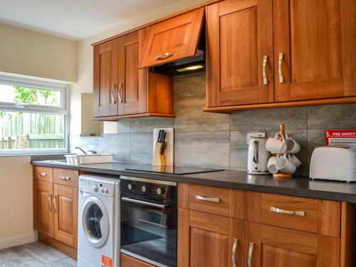 uma cozinha com armários de madeira e uma máquina de lavar louça em The Hydeaway em Whithorn