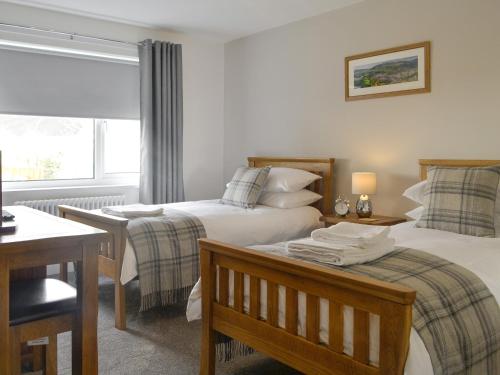 a bedroom with two beds and a table and a window at Rydal Cottage in Keswick