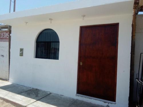 a brown door on a white building with a window at Hospedaje Vivanco 