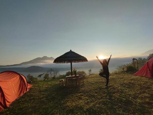 a person doing yoga on a hill next to tents at Kintamani Adventure 'Hide Away In Kintamani in Kintamani