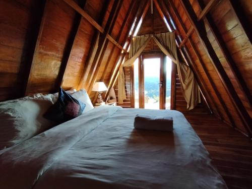 a large bed in a wooden room with a window at Kintamani Adventure 'The Hideway in Kintamani' in Kintamani