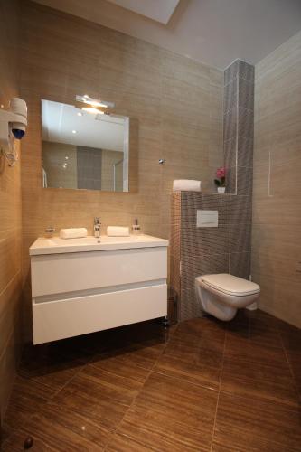a bathroom with a sink and a toilet and a mirror at Hotel Royal Gold City - Hotel Ruža in Sarajevo