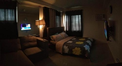 a bedroom with a bed and a couch and a television at Affordable place to stay near cebu city in Cebu City