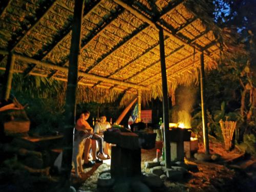 een groep mensen die onder een paviljoen met een vuur zitten bij Finca Los Guayacanes in Tena