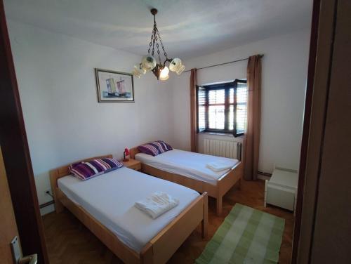 Cette chambre comprend deux lits et un lustre. dans l'établissement Apartment Dragi - 250 m from beach, à Supetar
