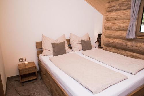 2 letti in una camera da letto con parete in legno di Blockhausen a Schwarzenberg am Bohmerwald