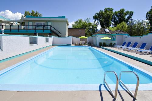 a large swimming pool with chairs and umbrellas at Tiki Shores Inn & Suites in Penticton