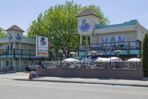 a building with tables and umbrellas in front of it at Tiki Shores Inn & Suites in Penticton