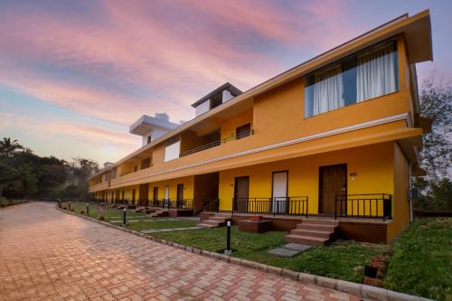 a large yellow building with a brick road at Sterling Karwar in Kārwār