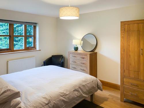 a bedroom with a bed and a mirror and a dresser at Ringland Cottage in Attlebridge