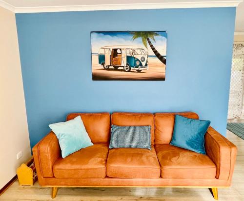 an orange couch with blue pillows on a blue wall at Decades in Port Willunga