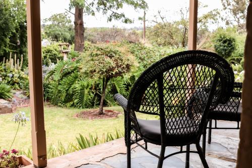 a chair sitting on a porch with a view of a garden at Cole-Brook Cottage Historic House in McLaren Vale