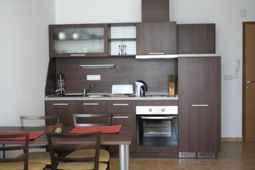 een keuken met houten kasten en een tafel met stoelen bij Apartments Helios in Pomorie