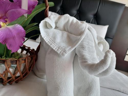 a white towel on a table next to a basket of flowers at Amici Miei Guest House in Patong Beach