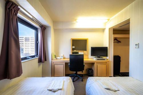 a hotel room with two beds and a desk with a computer at Ramada Encore by Wyndham Amagasaki in Amagasaki