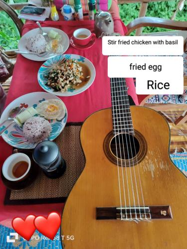 a guitar sitting on top of a table with food at Tulip Resort Pai in Pai