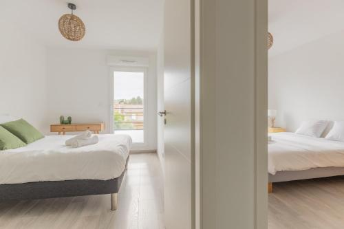 a white bedroom with two beds and a window at L'échappée - T3 de 67 m2 - Grande terrasse - Quartier ultra secure in Metz