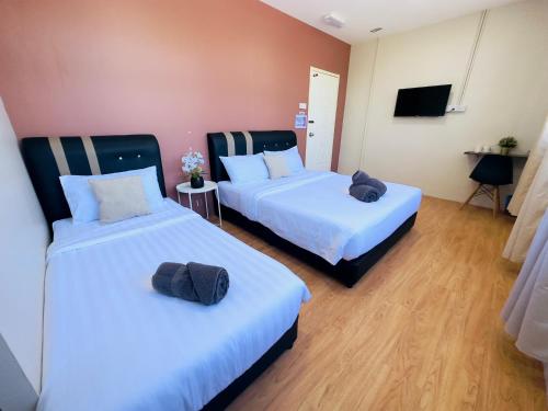 two beds in a hotel room with towels on them at Familia Motel Kangar in Kangar