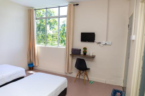 sypialnia z 2 łóżkami, oknem i krzesłem w obiekcie FAMILIA INN w mieście Kangar