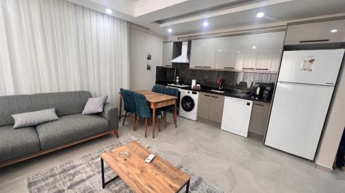 ein Wohnzimmer mit einem Sofa und einem Tisch sowie eine Küche in der Unterkunft SELİNTİ CİTY DAİRE 1 Suit in Gazipasa