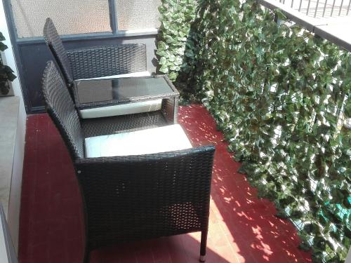 uma mesa e uma cadeira ao lado de uma sebe verde em Casa di Alessio, 6 posti letto a 200 mt dal mare em Albissola Marina