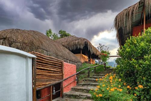 a group of huts with stairs and hay roofs at Deshadan Eco Valley Resort - An Eco friendly Mud House in Kanthalloor