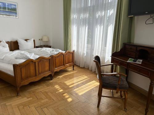 a bedroom with a bed and a desk and a chair at Jahrhunderthotel Leipzig in Leipzig