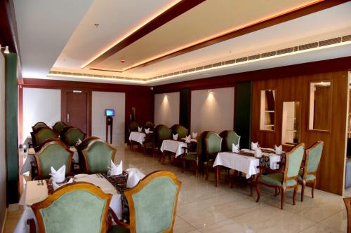 uma sala de jantar com mesas e cadeiras num restaurante em HOTEL EMERALD PALACE em Kottiyam