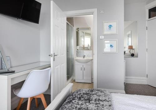 a white bedroom with a white desk and a white chair at Sealight in Pwllheli