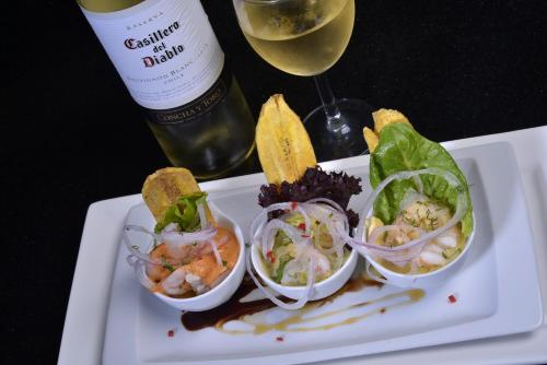 a white plate with a salad and a glass of wine at Hotel Ramada in Guayaquil