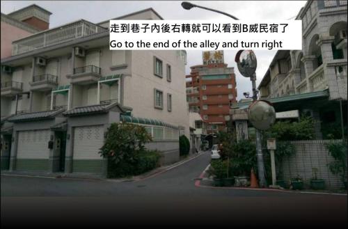 a street with buildings and a sign that says go to the end of the alley at B-wei B&B in Hualien City