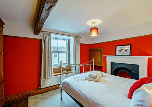 a bedroom with red walls and a bed with a fireplace at Marys Cottage in Hawes
