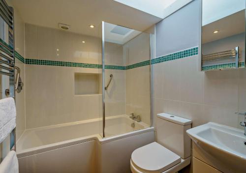 a bathroom with a shower and a toilet and a sink at Marys Cottage in Hawes