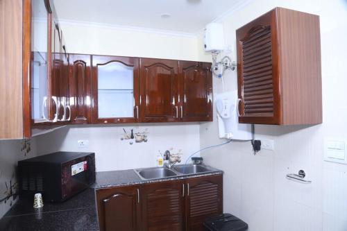 cocina con armarios de madera, fregadero y microondas en Divine India Service Apartment 3Bhk,B57 Sarita Vihar,Apollo en Nueva Delhi