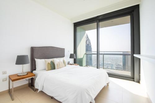 um quarto com uma cama branca e uma grande janela em Burj Vista, Downtown Dubai Collection em Dubai