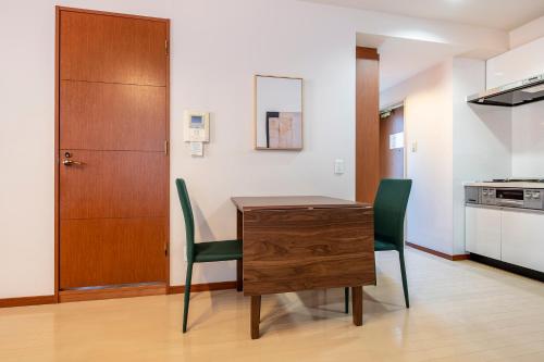 a kitchen with a wooden table and two green chairs at Granado Roppongi in Tokyo