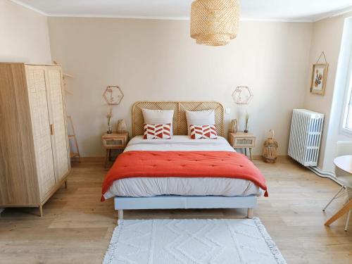 Schlafzimmer mit einem Bett mit roter Bettwäsche und Kissen in der Unterkunft Chez Lucy&Nico in Verfeil