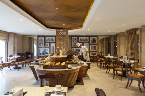 a chef preparing food in a restaurant with tables and chairs at Trident Bhubaneswar in Bhubaneshwar