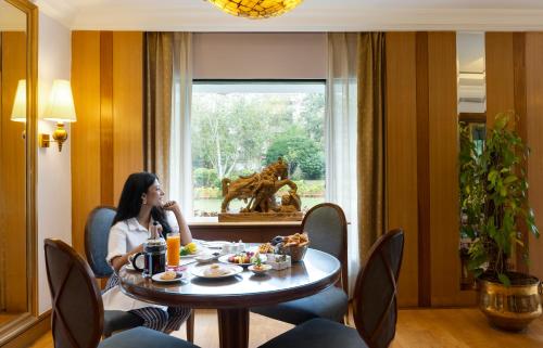 a woman sitting at a table in a room at Trident Bhubaneswar in Bhubaneshwar