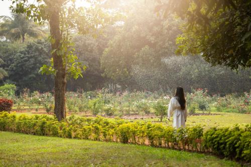 a woman walking through a garden with flowers at Trident Bhubaneswar in Bhubaneshwar