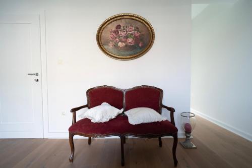 una silla roja con 2 almohadas en una habitación en Nomad Rooms, en Mostar