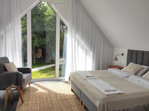 a bedroom with a bed and a chair and a window at Źródlana Apartamenty - całoroczne domy na wyłączność in Odargowo