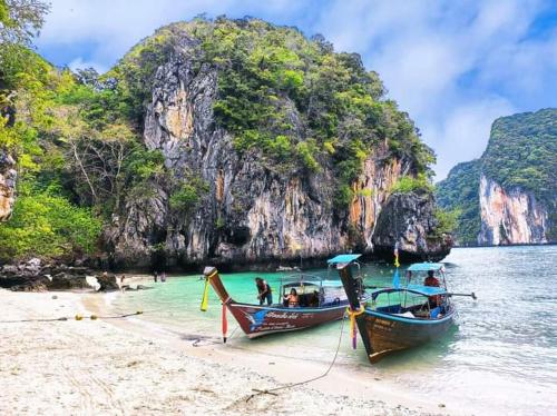 twee boten op een strand naast een berg bij Ko Yao Noi Sabai Bungalows in Ko Yao Noi