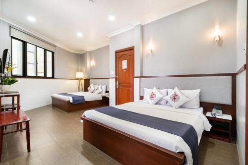 una habitación de hotel con dos camas y una mesa en Văn Hoa Hotel, en Ho Chi Minh