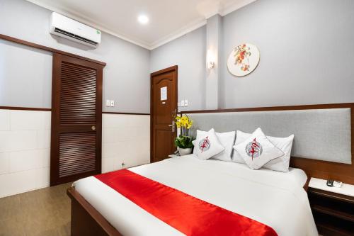 Un dormitorio con una gran cama blanca con una manta roja. en Văn Hoa Hotel, en Ho Chi Minh