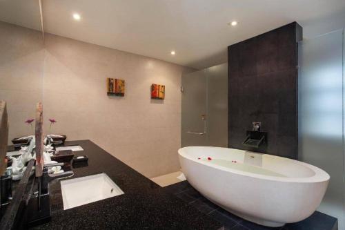 La salle de bains est pourvue d'une grande baignoire blanche et d'un comptoir noir. dans l'établissement The Residence Villa 203, à Bang Tao Beach